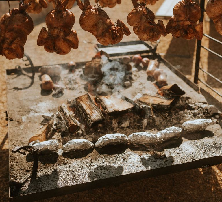 Meat hanging from BBQ for food at rustic farm wedding in Dorset