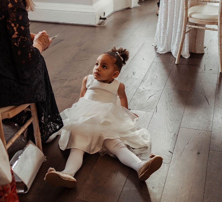 Flower girl wears white tea length dress with her hair in a top knot