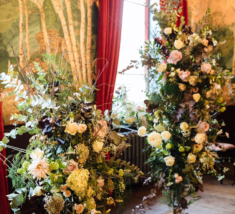 Large floral displays of roses and other greenery at the altar 