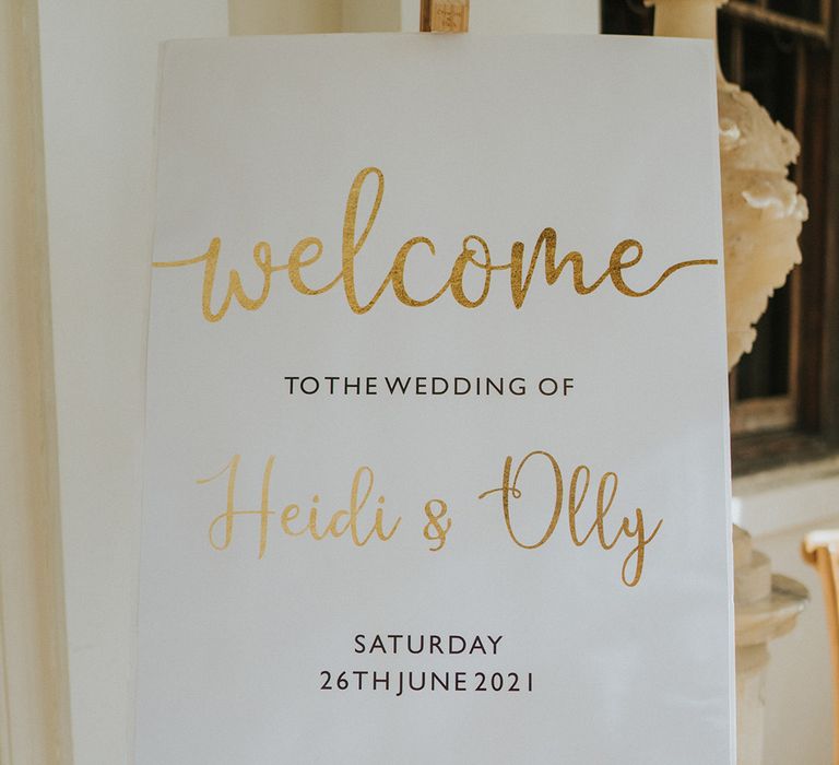 White, gold and black welcome wedding sign on wooden easel for outdoor wedding at country house