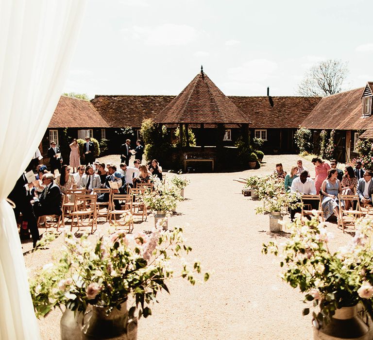 Summer outdoor wedding ceremony decorated with vintage milk churns with flowers for home wedding