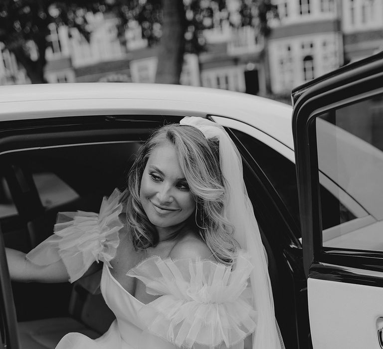 Bride in ruffle sleeve wedding dress exits the wedding car