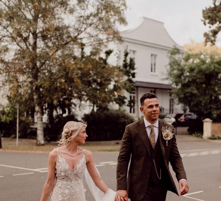 Bride in made With Love Bridal wedding dress walks with groom in brown suit