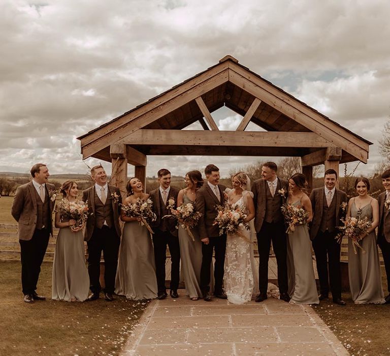 Wedding party smile and pose together for rustic wedding at Eden Barn with orange and neutral colour scheme