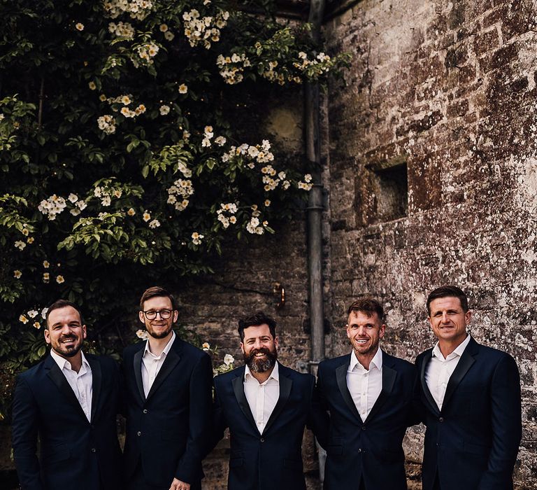 Groom and groomsmen in matching blue suits with black satin lapels for outdoor wedding at Athelhampton House 