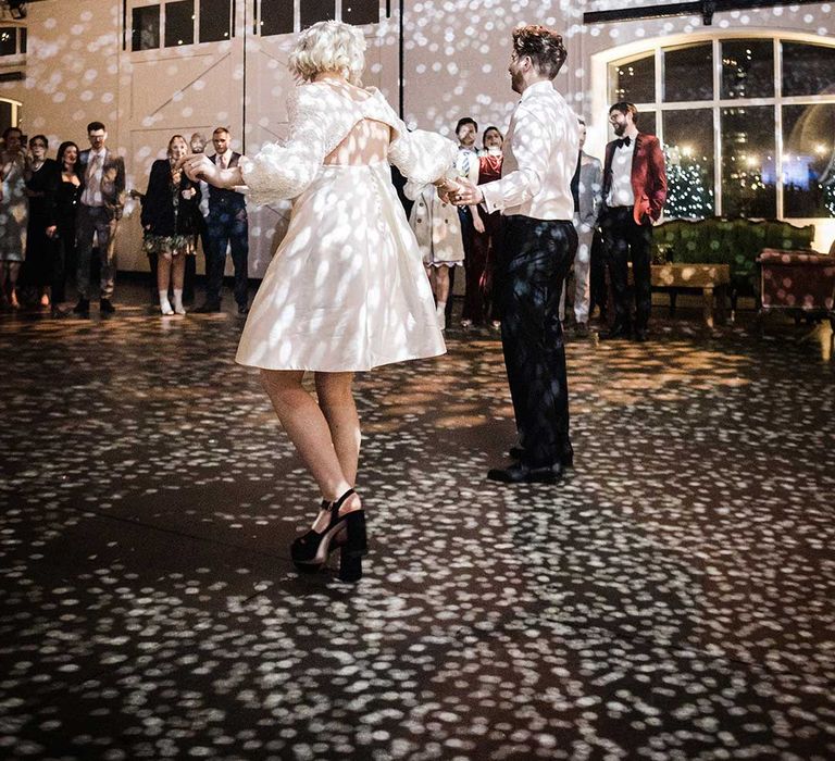 Bride in open back short wedding dress and groom doing their first dance