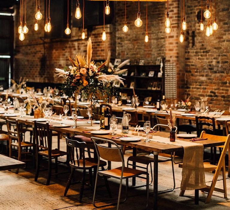 Hanging festoon lighting over the industrial style banquet tables decorated with dried flowers at White Syke Fields venue 