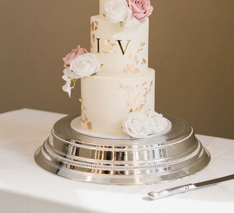 Three tier wedding cake finished with white frosting, gold personalised lettering and rose decor