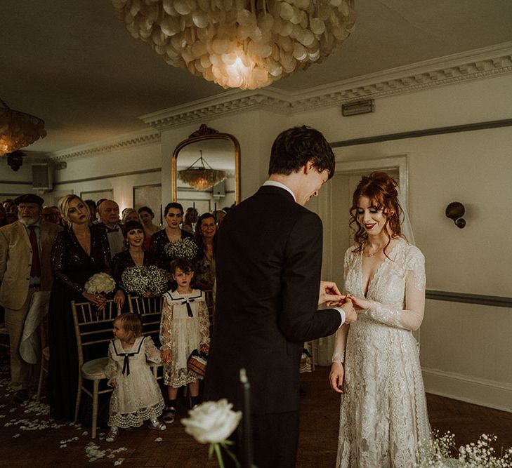 Groom puts wedding ring on his bride at Belair House during gothic and romantic wedding ceremony