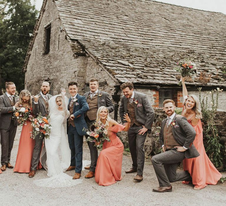 Bride and groom do funny poses with their groomsmen and bridesmaids in coral bridesmaid dresses