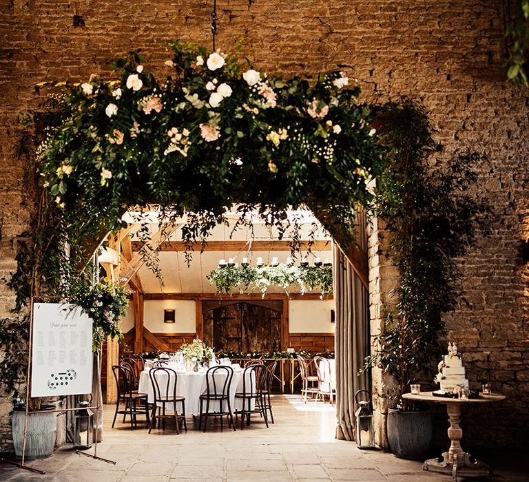 Cripps Barn rustic wedding venue with foliage, pink and white wedding flowers, rustic wedding cake and copper frame table plan