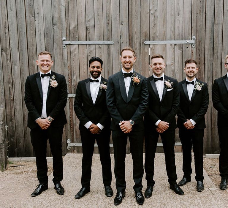 Groom poses with the groomsmen in black tie 