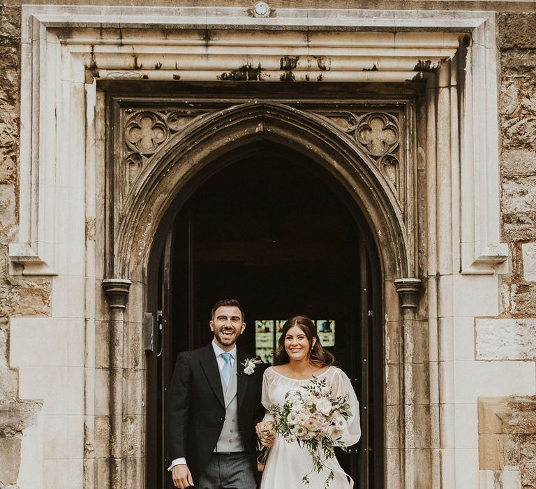 Bride and groom exit the church after their traditional church wedding ceremony 