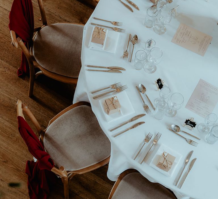 Round tables with gold cutlery, wrapped up present wedding favours, and list of wines from around the world