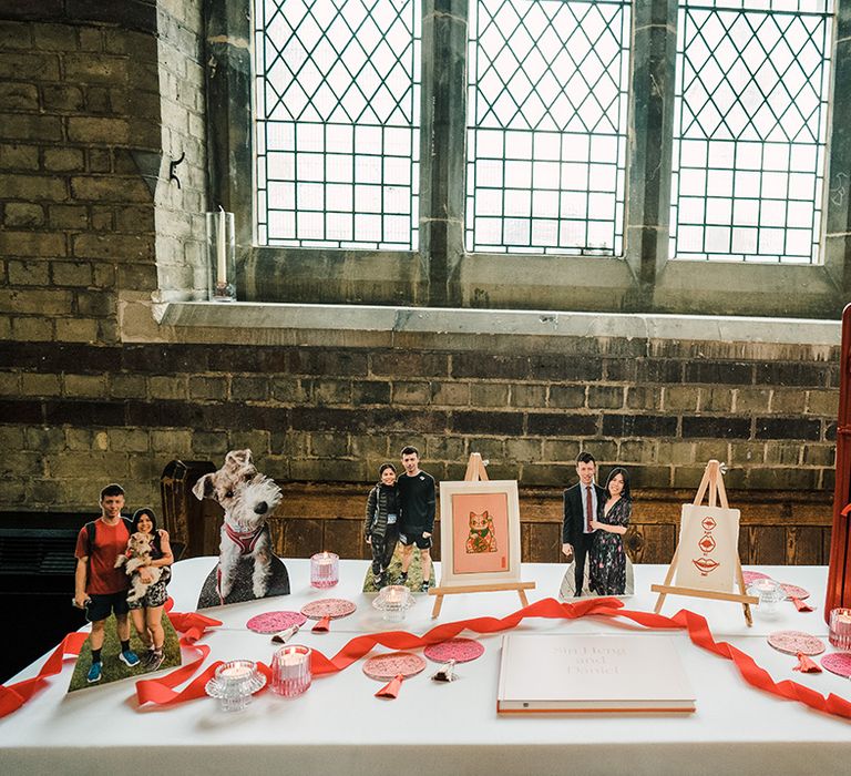 Red postbox beside cardboard cutouts of bride & groom and their dog complete with colourful ribbon on white tablecloth 