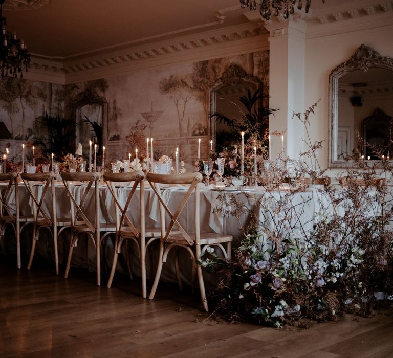 Minimalistic, luxe wedding tablescape with tapered candles, chandeliers, large dried flower and rose floral arrangements and crisp white tablecloth 