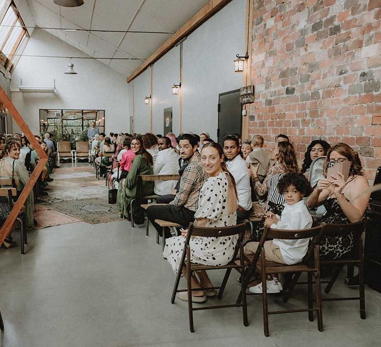 Industrial style ceremony venue complete with exposed brick walls and green foliage to the front 