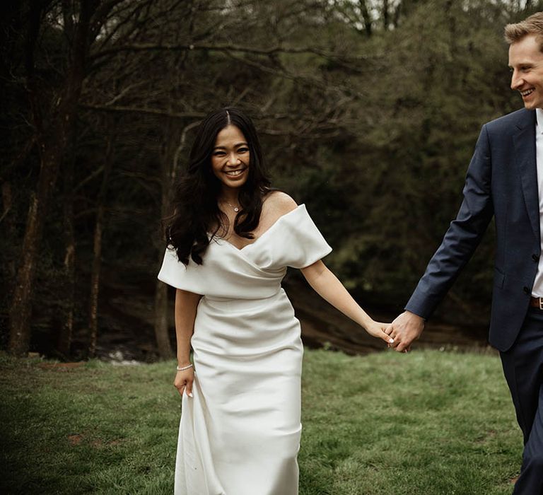 The bride and groom walk together holding hands on their wedding day for cute coupe portraits 