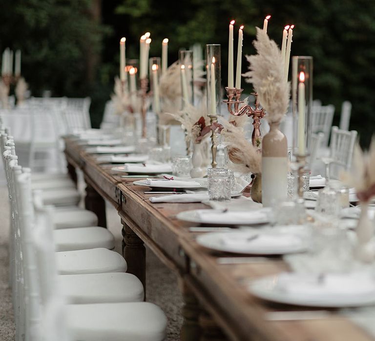 Rose gold candelabras line wooden banquet tables for outdoor boho wedding in Italy 