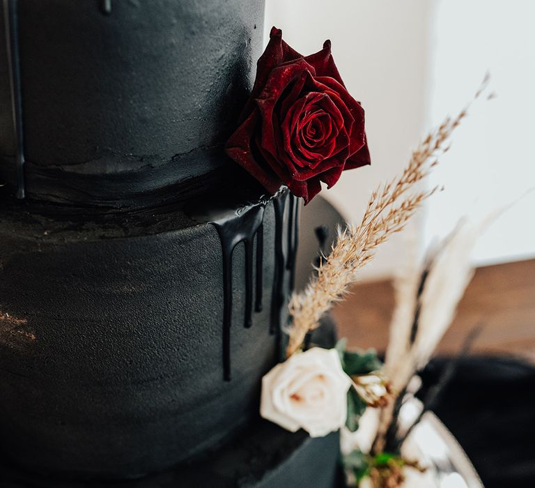 Black wedding cake with drip icing red and white rose for gothic wedding at Parley Manor 