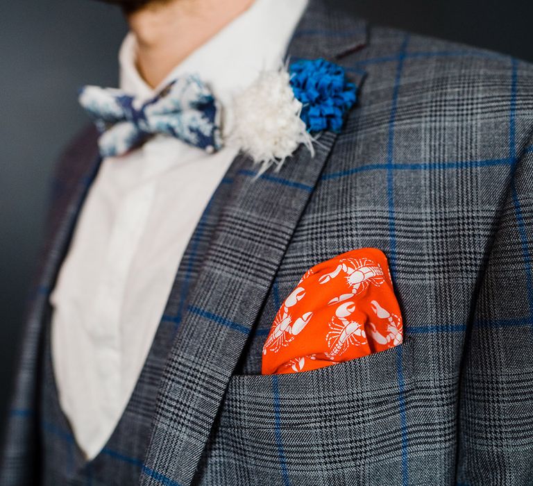 Grey and blue checkered suit worn but groom with bright orange pocket square with lobsters and blue and white floral patterned bow tie groom accessories 