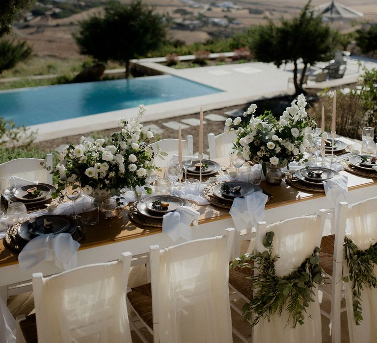 Private villa wedding with white and green floral tablescape, swimming pool and views of the Grecian hills