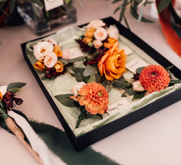 Orange dahlia and rose buttonholes for the wedding with autumnal colour palette for September wedding 