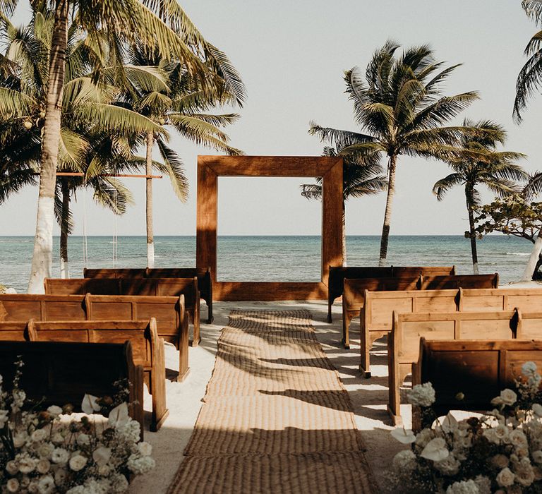 blue venado beach wedding ceremony with wooden church pews and minimalist white wedding flowers 