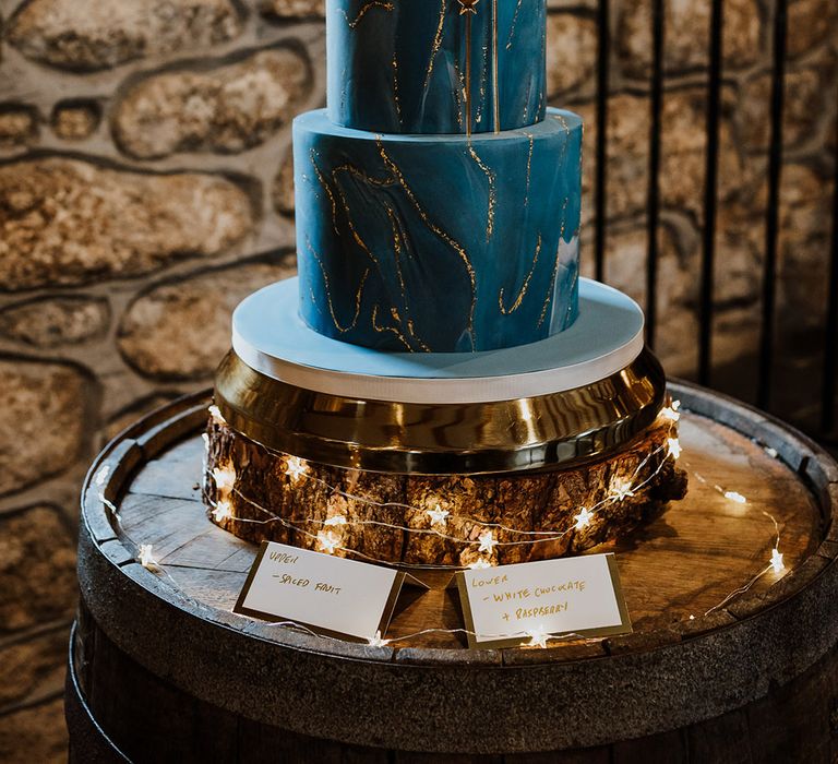 Two tier blue wedding cake with sparkly gold details and crescent moon cake topper for winter wedding 