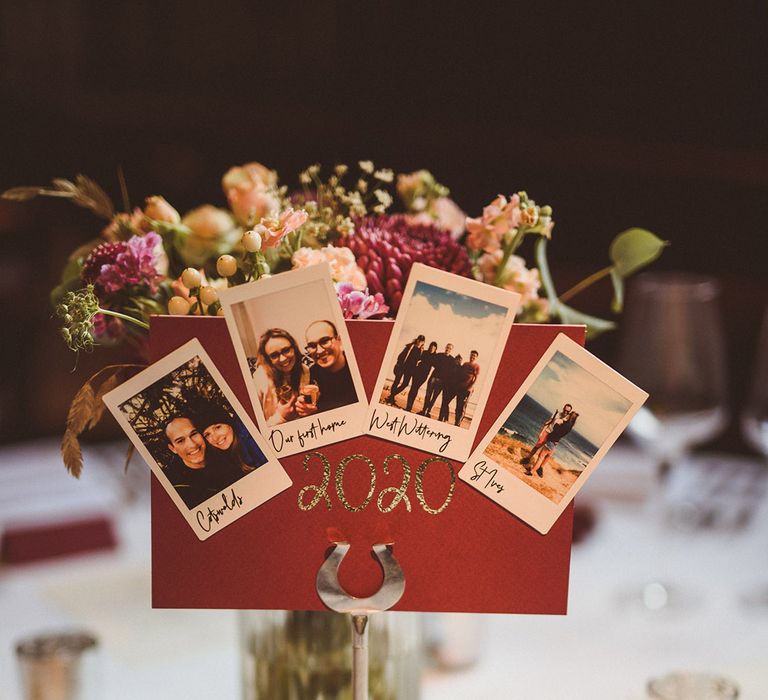 Burgundy wedding table name sign based on different years with polaroid pictures of the couple 