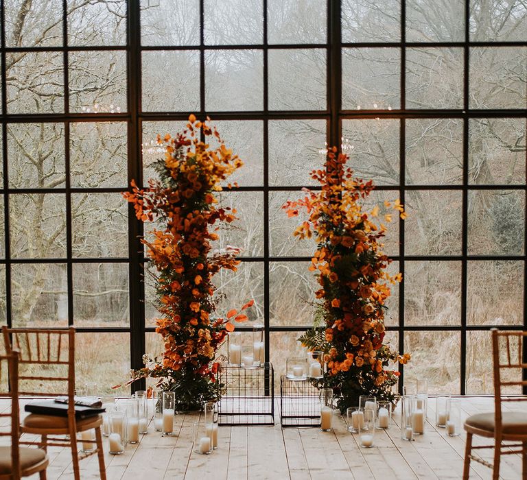 Orange autumnal wedding flower column decorations at the altar for Hidden River Barns wedding in Carlisle 