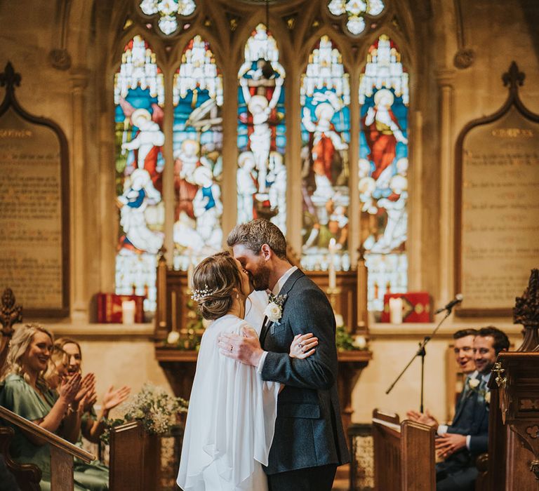 The bride and groom share their first kiss as a married couple at their church wedding 