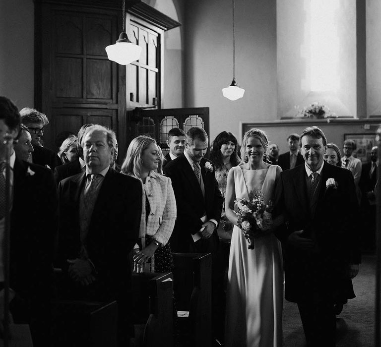 The father of the bride walks the bride down the aisle to the groom 