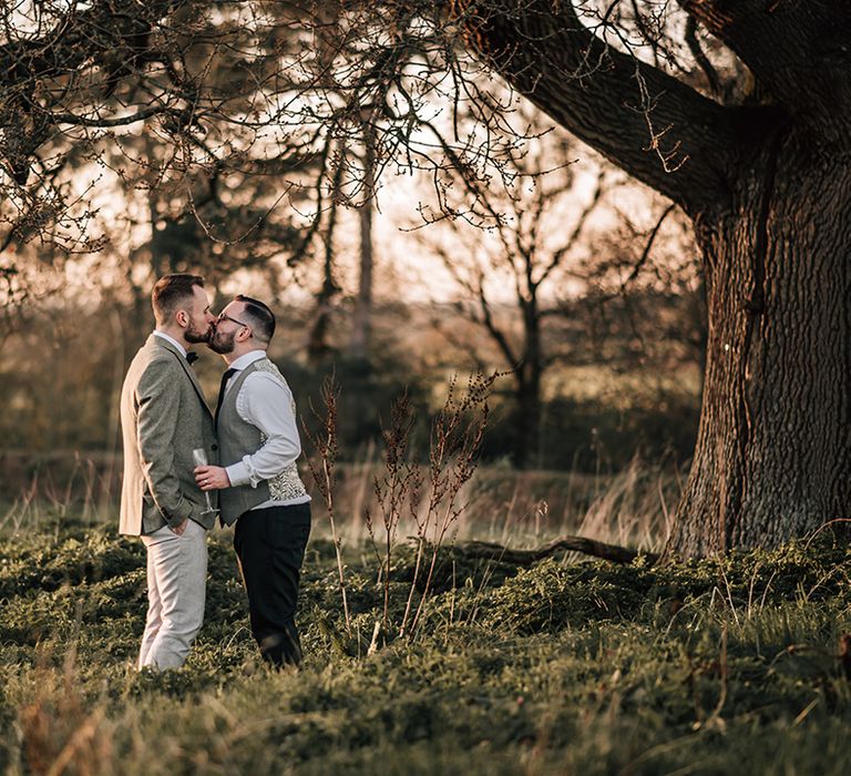 LGBTQIA+ wedding with two grooms sharing a kiss on their wedding day during the sunset 