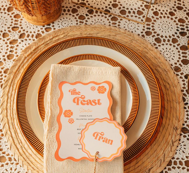 Wicker place mat with orange and black wedding plates with retro wedding place names and menus 