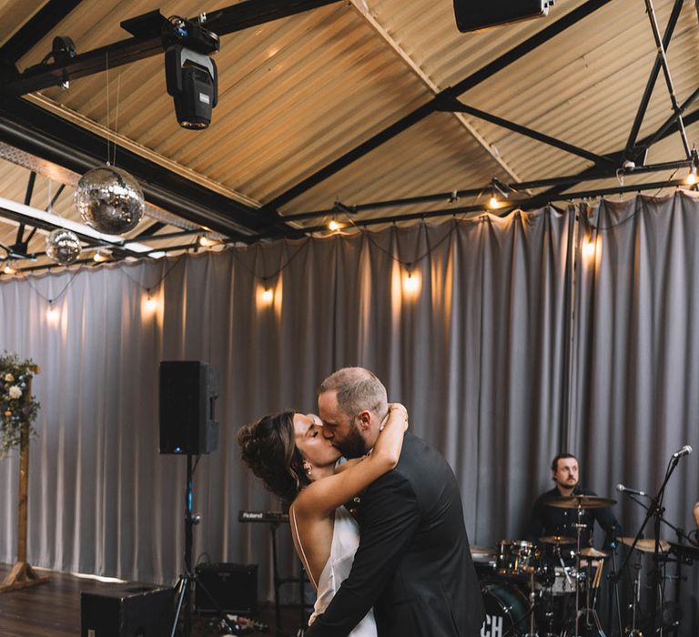 The bride and groom have their first dance in front of the live wedding band 