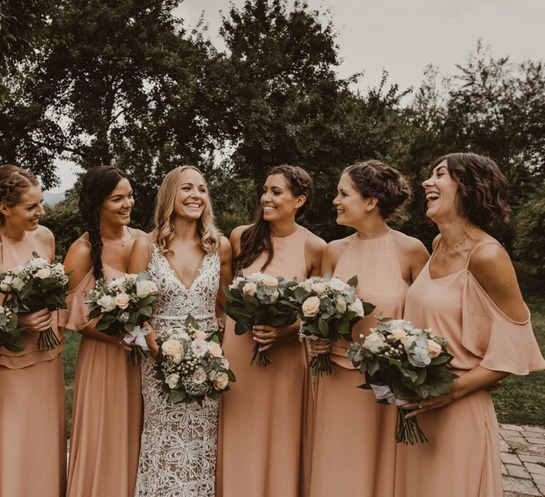 Bridesmaids in mismatched halter neck and off the shoulder peach bridesmaid dresses with the bride 