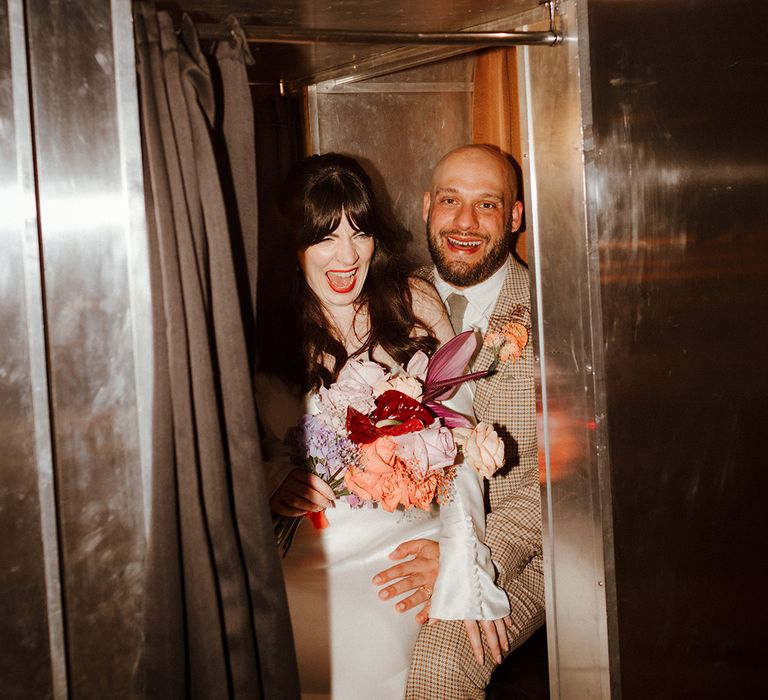 The bride and groom sit in their retro wedding Photo Booth 