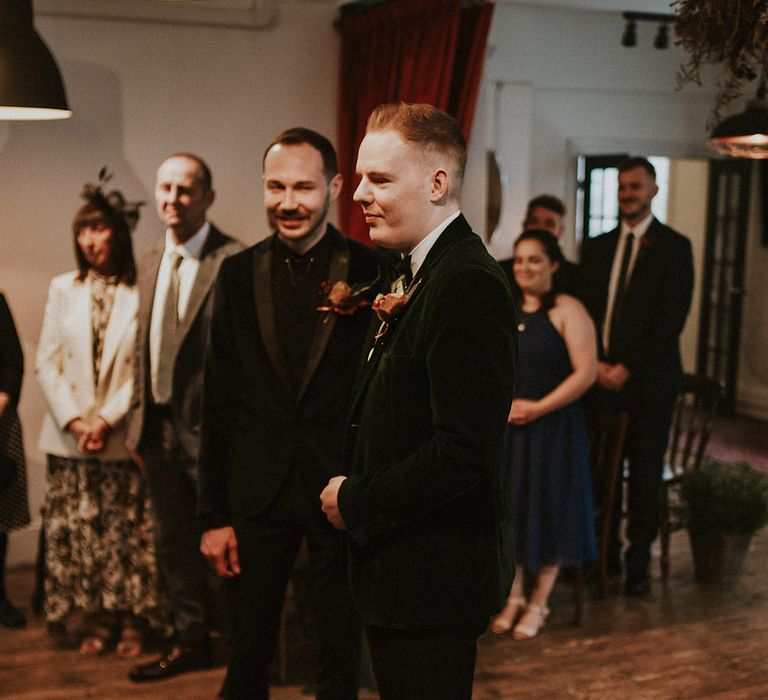 Two grooms at their same sex gay wedding wearing velvet suit jackets 