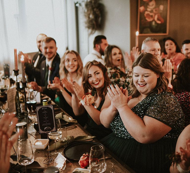 The wedding guests enjoy the wedding reception as they applaud the wedding speeches 