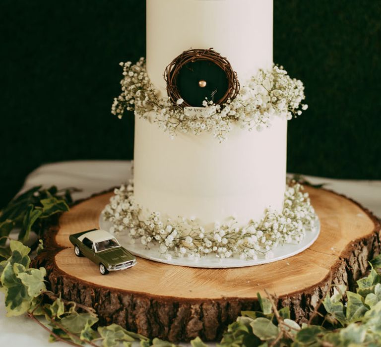 Two tier white frosted wedding cake with hobbit door decorated with gypsophila 