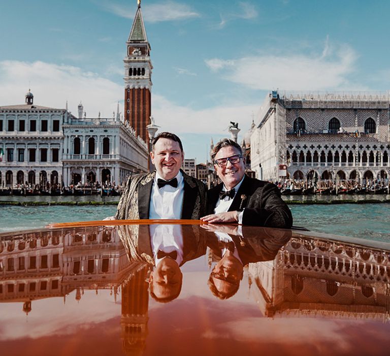 Two grooms riding on a boat at their Venice destination wedding for incredible couple portrait photos 