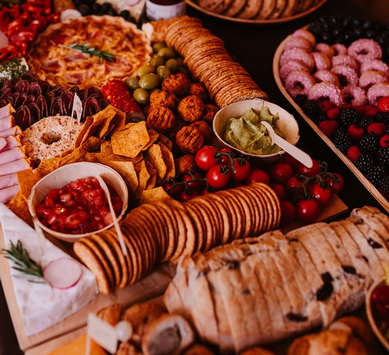 Grazing table wedding food serving idea with quiche, crackers, berries, doughnuts, fruit and dips 