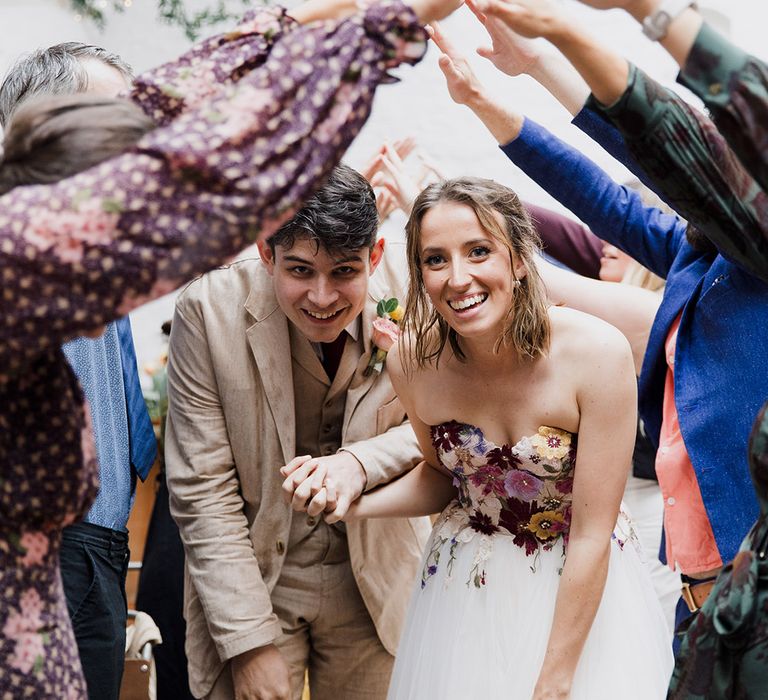 Bride and groom walking under the guests arms as they exit their wedding ceremony 