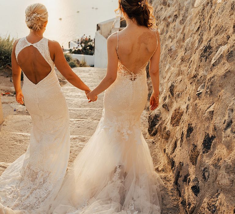 Santorini destination wedding with two brides walking together in boho lace wedding dresses