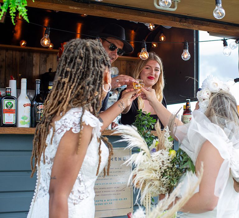 The two brides take a shot together after their wedding ceremony to toast to their marriage 