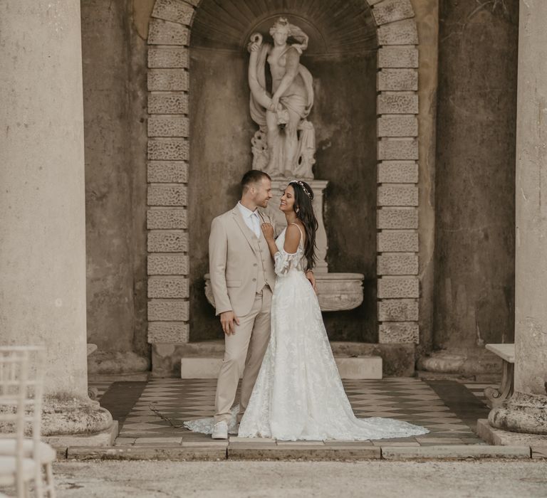 Groom in beige suit and white trainers and bride in lace wedding dress