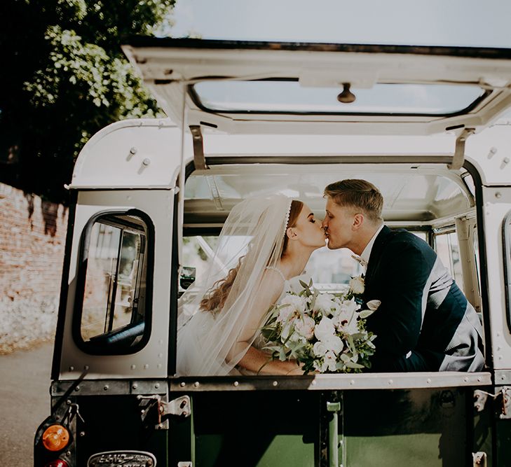 Bride and groom kissing in their jeep wedding car 