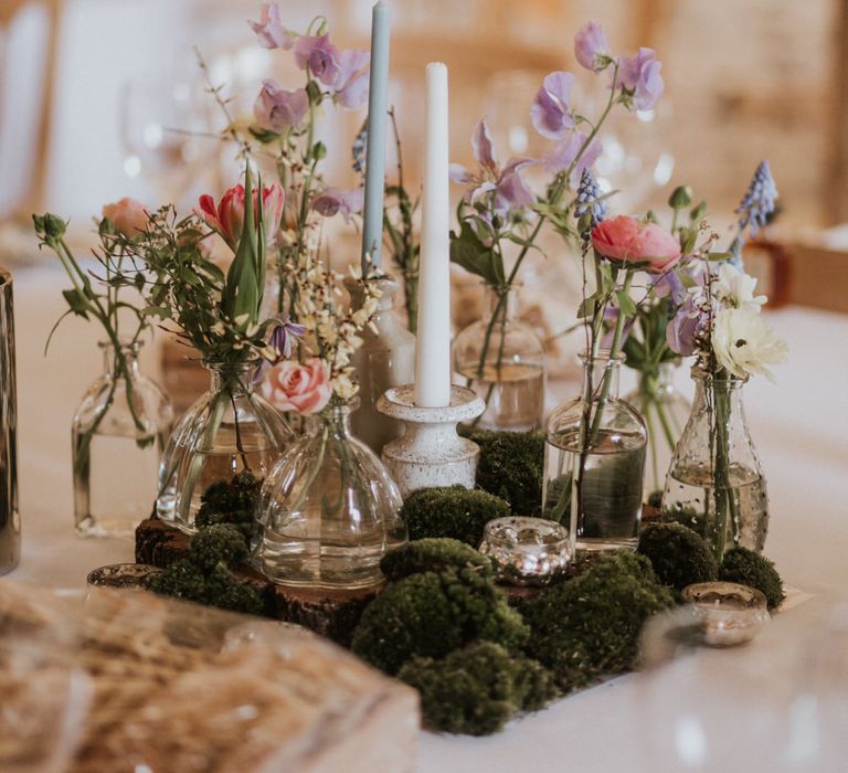 Botanical centrepiece with floral stems in jars and moss 