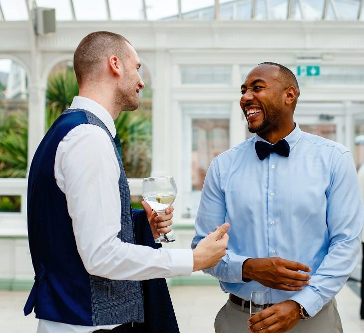 Groom and wedding guest laughing 